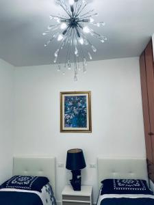 1 dormitorio con 2 camas y lámpara de araña en CASA DEI FIORI, en Somma Lombardo