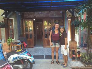 two women are standing in front of a house at Sun smile(cafe & homestay) in Ubon Ratchathani