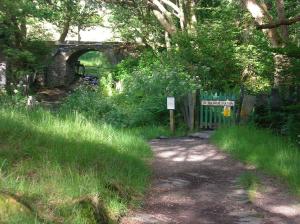 uma estrada de terra com um portão e uma ponte em The Dolgoch em Bryn-crug