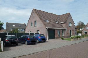 drie auto's geparkeerd op een parkeerplaats voor een huis bij Effe-Zoutelande B&B in Zoutelande