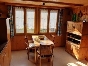 a kitchen with a wooden table and chairs and windows at Chalet Am Fels in Innertkirchen