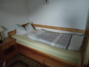 Bett mit einem Kopfteil aus Holz und Kissen darauf in der Unterkunft Ferienwohnung in Bohndorf