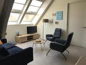 a living room with three chairs and a tv at Hendrikhof Appartement 3 ‘het Gebint’ in Westkapelle