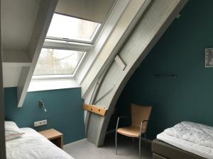 an attic bedroom with a bed and a window at Hendrikhof Appartement 3 ‘het Gebint’ in Westkapelle