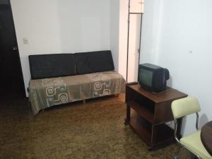 1 dormitorio con 1 cama, TV y silla en Residencia La Perla en Mar del Plata