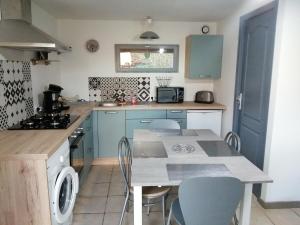 a kitchen with blue cabinets and a table and chairs at Au fil de l'eau in Conchy-sur-Canche