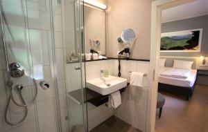 a bathroom with a sink and a shower and a bed at Jugendstilhotel Trifels in Annweiler am Trifels