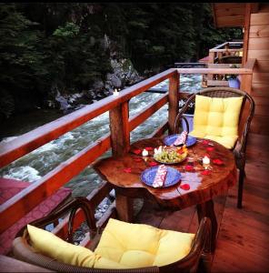Çamlıhemşin的住宿－Hoşdere Suit，甲板上配有一张木桌和椅子,配有桌椅
