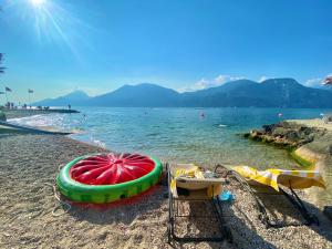 a beach with two chairs and an umbrella on the shore at Hotel Du Lac - Relax Attitude Hotel in Brenzone sul Garda