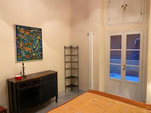 a bedroom with a painting on the wall and a dresser at Renovated apartment with 3 bedrooms in an historic palazzo between port and old town in Livorno