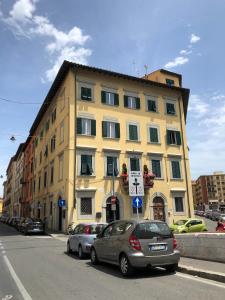 a yellow building with cars parked in front of it at Renovated apartment with 3 bedrooms in an historic palazzo between port and old town in Livorno