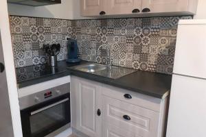 a small kitchen with a sink and a refrigerator at T2 Rez de chaussée climatisé jardin parking privé in Balaruc-les-Bains