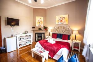 1 dormitorio con 1 cama con manta roja y chimenea en Flametree Guesthouse, en Swellendam