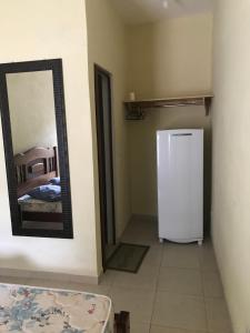 ein Zimmer mit Kühlschrank und Spiegel an der Wand in der Unterkunft Suites em Maresias in Maresias