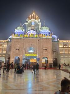 a large building with people in front of it at night at Hotel RUJHAN - Just 2 Minute walking Distance From Golden Temple in Amritsar