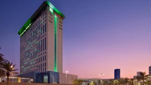 Un edificio alto con una striscia verde sopra di Holiday Inn & Suites - Dubai Festival City Mall, an IHG Hotel a Dubai