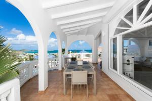 een balkon met een tafel en stoelen en de oceaan bij Orient Bay Villa Rentals St Martin in Orient Bay
