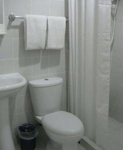 a bathroom with a toilet and a shower with towels at Hotel Pier Cuatro in Cebu City