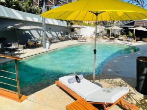 einen Pool mit einem gelben Regenschirm und einem Liegestuhl mit einem Telefon in der Unterkunft BOMA LifeStyle Hotel in Dakar