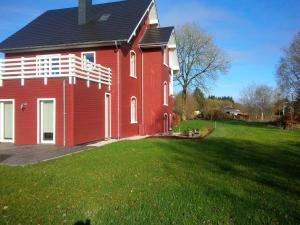 una gran casa roja con un patio de hierba delante de ella en Rod Hus en Sourbrodt