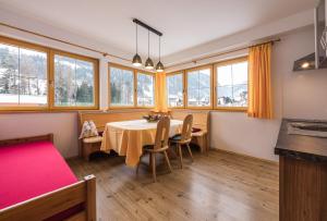 a dining room with a table and chairs and windows at Gitschberg - Appartements in Vandoies