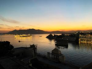 a sunset over a body of water with boats in it at Hotel The Tiger in Udaipur