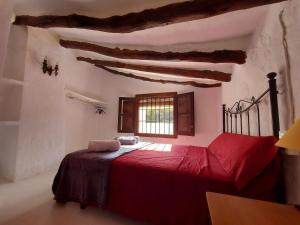 sypialnia z czerwonym łóżkiem i oknem w obiekcie Luby Cortijo Las Eras w mieście Lubrín