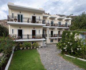 a large white building with balconies and a yard at Aretousa in Sougia
