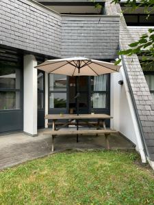 a picnic table with an umbrella in front of a building at Le repère du Cerf T2 Résidence Royal Milan ST Lary Soulan in Saint-Lary-Soulan
