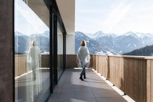 una donna in piedi su un balcone che guarda le montagne di The one and only a Serfaus