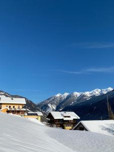 a snow covered slope with houses and mountains in the background at Pension Pichlerhof in Stall