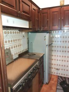 a kitchen with wooden cabinets and a refrigerator at ALLOGGIO ARCOBALENO in Brossasco
