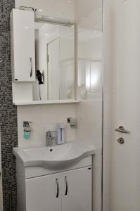 a white bathroom with a sink and a mirror at Apartman STUPOVI Zlatibor in Zlatibor