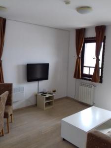 sala de estar con TV de pantalla plana y mesa en Green Oaza Apartment, en Fojnica