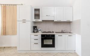 a kitchen with white cabinets and a black oven at Iliada Villas in Agios Prokopios