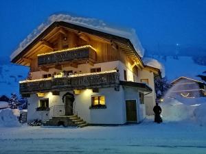 a house with a balcony in the snow at night at Gästehaus die geislerin in Gerlos