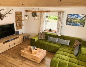 ein Wohnzimmer mit einem grünen Sofa und einem TV in der Unterkunft Ferienhaus Bergvagabund in Schönau am Königssee