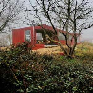 a red house sitting on top of a field at rodune in Koksijde