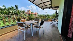 a table and chairs on a balcony with a view at Nessies Nagaon in Alibaug