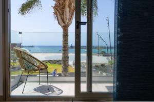 una silla frente a una ventana con una palmera en Apartamento Paula con vistas al mar en Arrecife