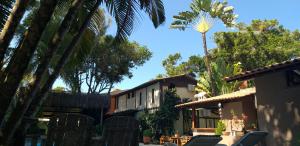 a house with a palm tree in front of it at Pousada Macunaima in Arraial d'Ajuda