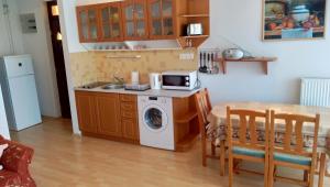 シオーフォクにあるDaniella apartman Siófokのキッチン(洗濯機、テーブル、電子レンジ付)