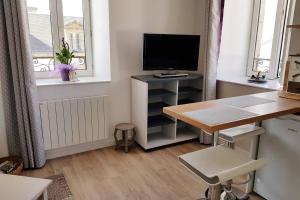 ein Wohnzimmer mit einem Schreibtisch, einem TV und einem Tisch in der Unterkunft Studio Cosy 3 étoiles centre Plouharnel proche mer in Plouharnel