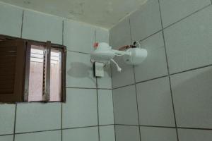 a bathroom with a light on a tiled wall at Ótima Suíte - Ponta Negra in Natal +3 photos
