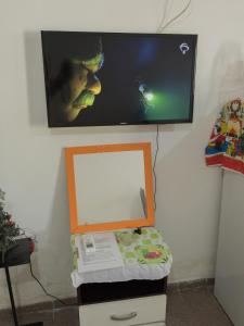 a flat screen tv on a wall with a mirror at Ótima Suíte - Ponta Negra in Natal