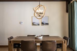 une table à manger avec des chaises et un lustre dans l'établissement Le Sous-Bois (Les Manoirs) Mont-Tremblant, à Mont-Tremblant