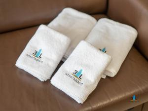 4 białe ręczniki siedzące na brązowej kanapie w obiekcie 3L Apartments Olympic Park w Kołobrzegu +33 zdjęcia