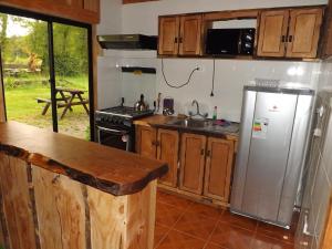 a kitchen with a stainless steel refrigerator and a sink at Cabañas Los Alamos Neltume in Neltume