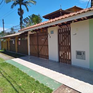 Casa de praia Bertioga SP Wi-Fi Fibra Home Office في بيرتيوغا: منزل به سياج خشبي وبوابة