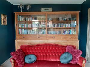 um sofá vermelho num quarto com uma estante de livros em Vakantiehuis Louiselotte em Alveringem
